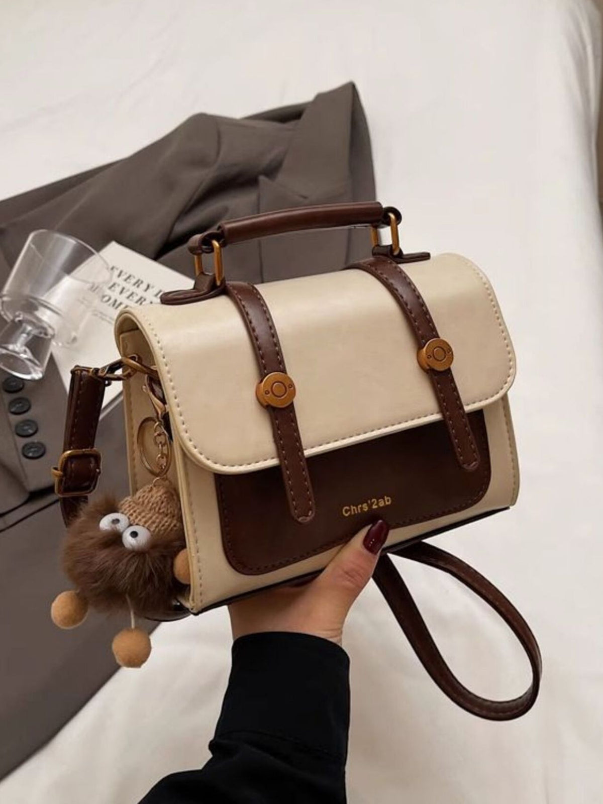 Front view of cream and brown flap crossbody bag with shoulder strap