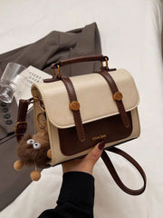 Front view of cream and brown flap crossbody bag with shoulder strap