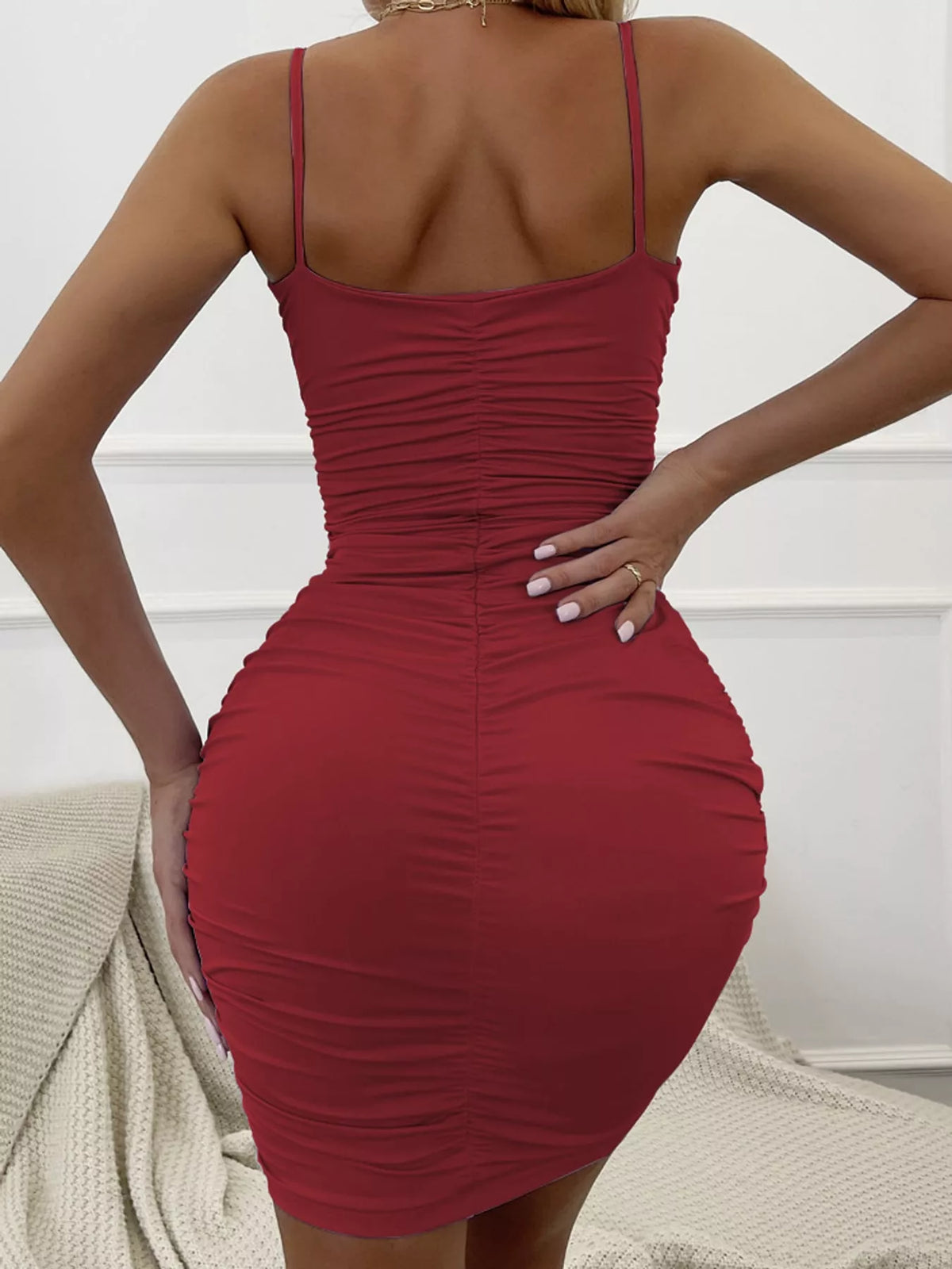 Rear view of the burgundy mini dress on a model, showing the slim straps and ruched back.