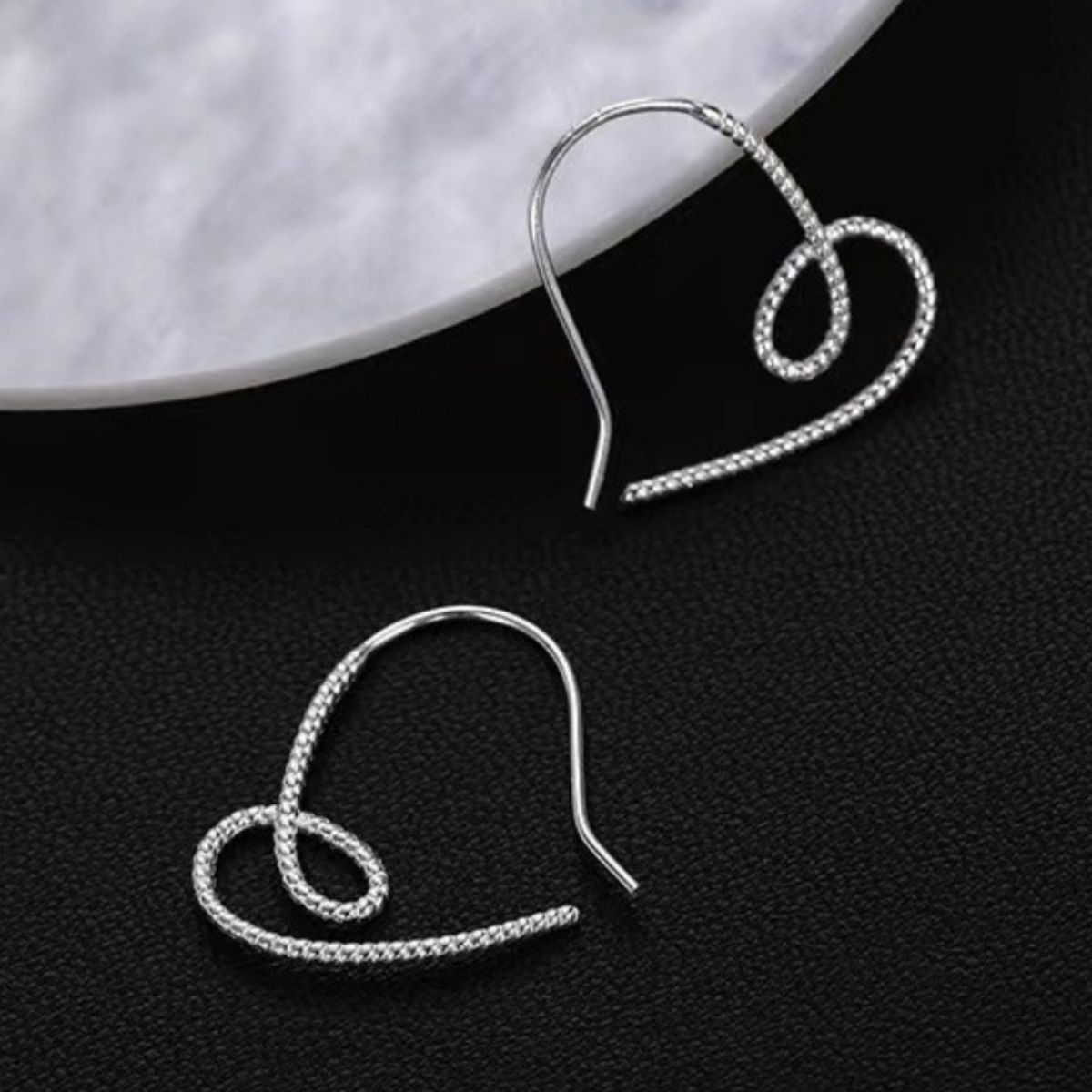 Close view of a single silver heart-shaped dangle earring