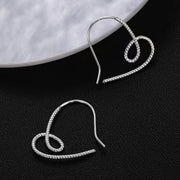 Close view of a single silver heart-shaped dangle earring