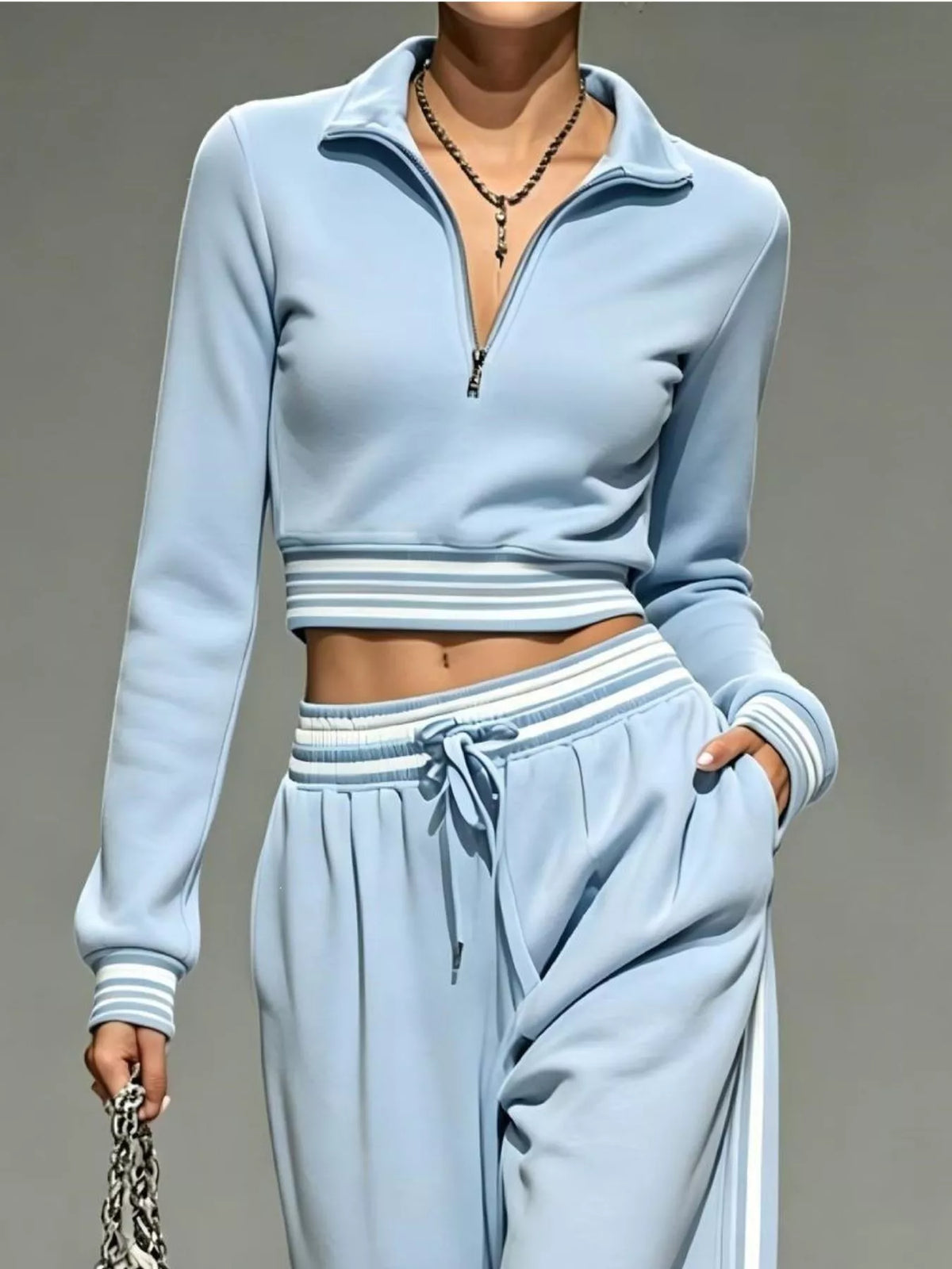 Light blue half-zip cropped top and pants set shown from waist up with striped cuffs
