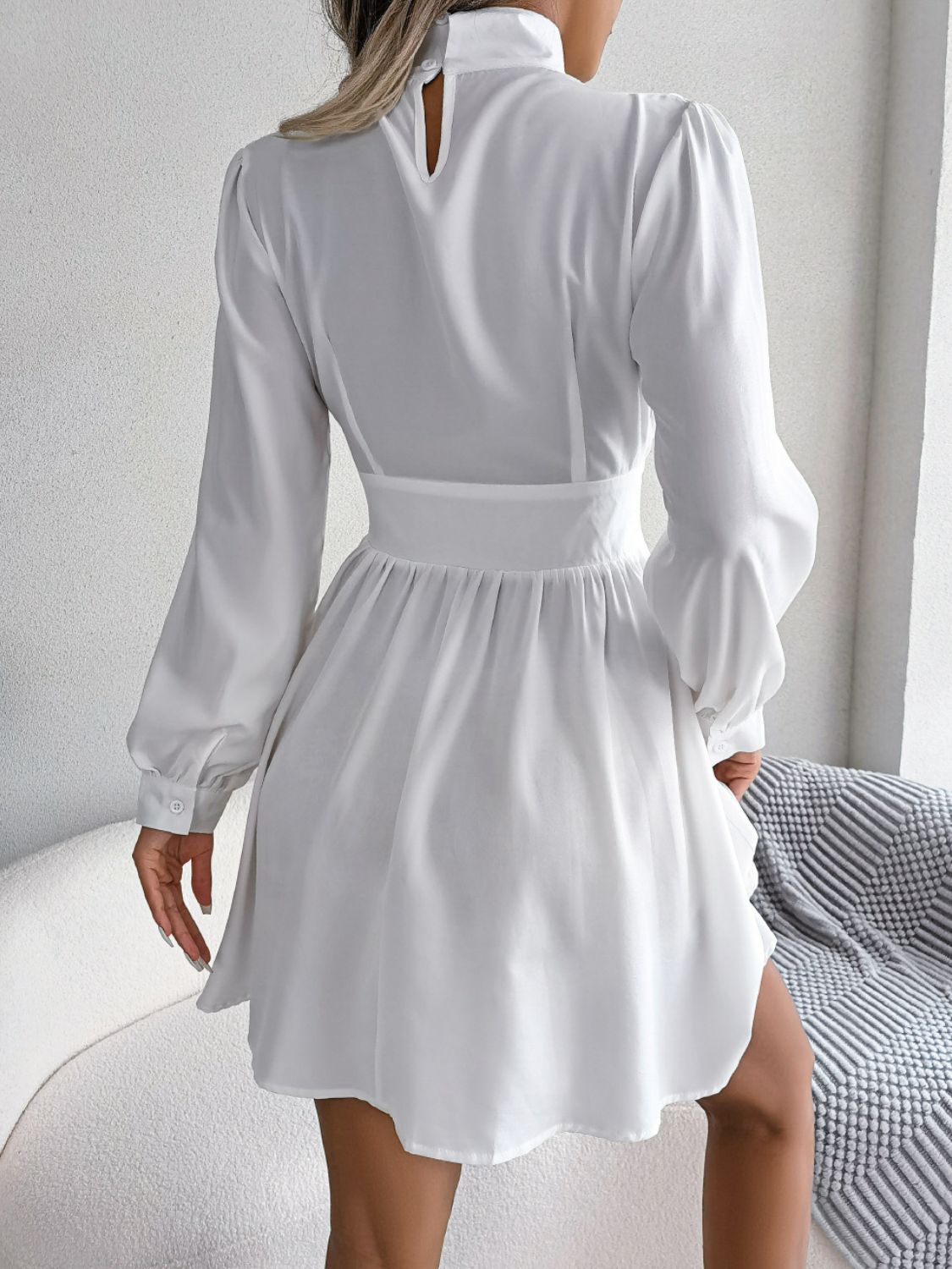 Model in black cutout turtleneck A-line mini dress, front view