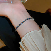 Blue-stone bracelet worn close to the wrist beneath a white sleeve
