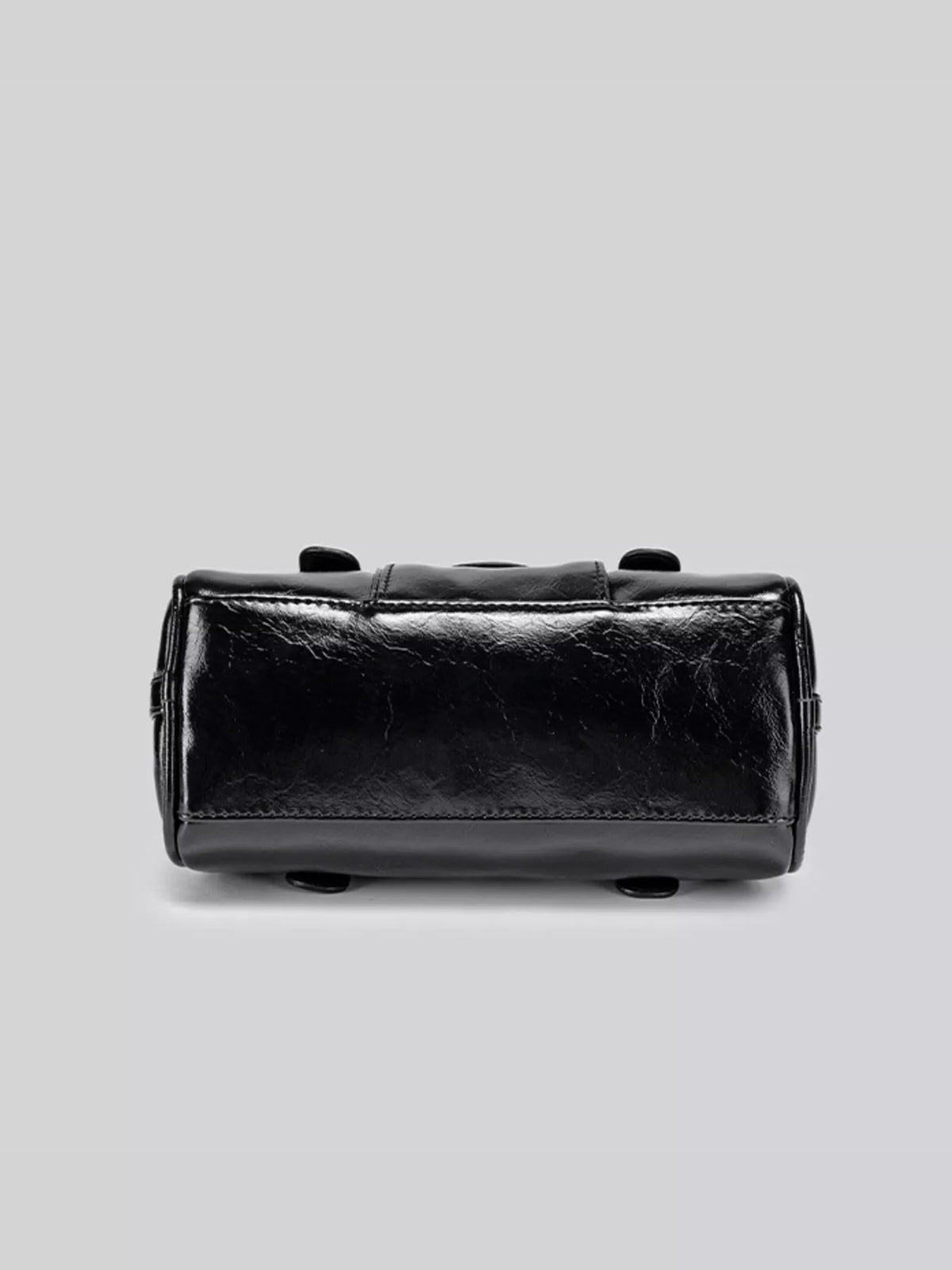 Bottom view of the black patent-look Boston bag with its base panel and feet visible.