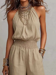 Close view of beige jumpsuit halter neckline and smocked waist
