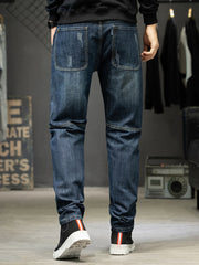 Back view of men's dark blue slim-fit jeans with two patch pockets and faded details