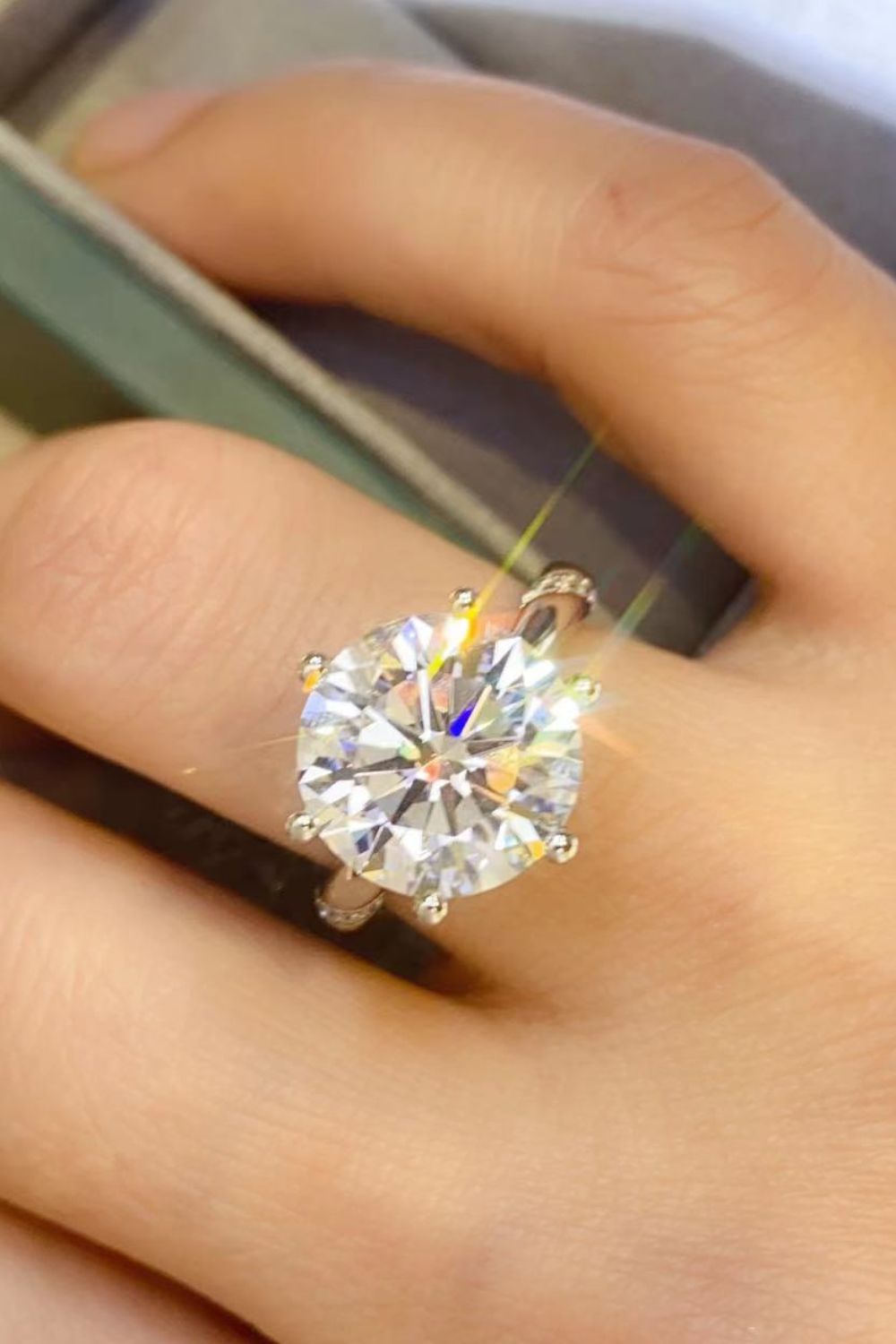 Angled close-up of the six-prong solitaire worn on a hand.