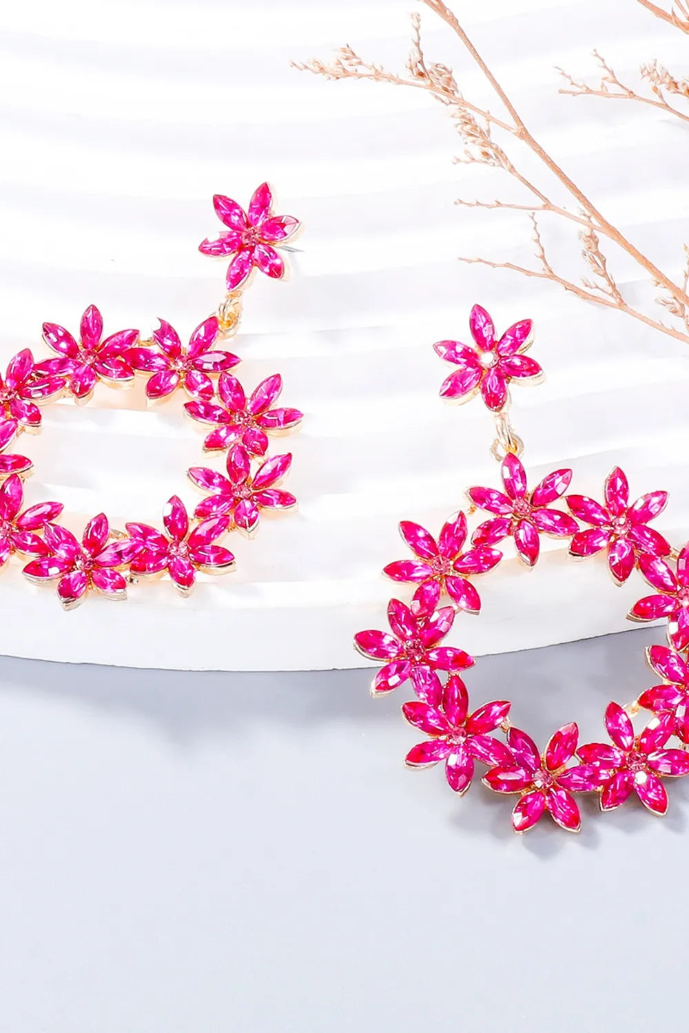 Bright pink flower-shaped dangle earrings displayed on white