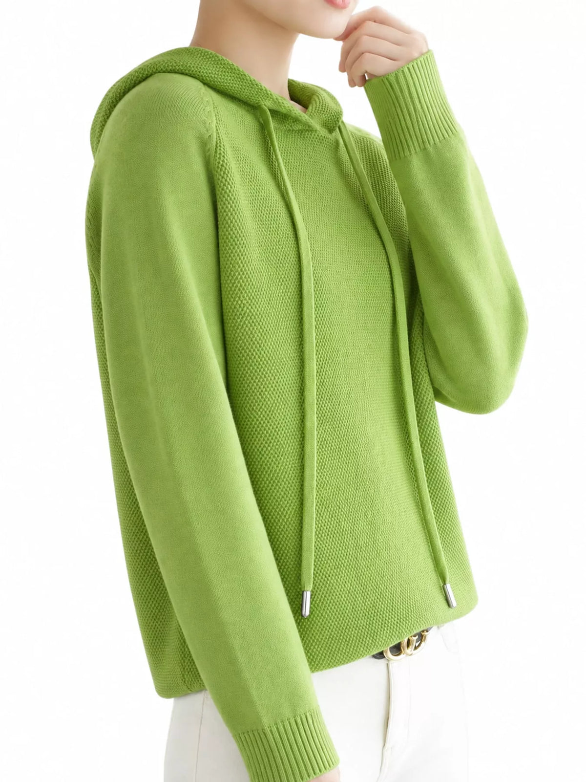 Angled view of the light green hooded sweater with a hand raised near the chin.