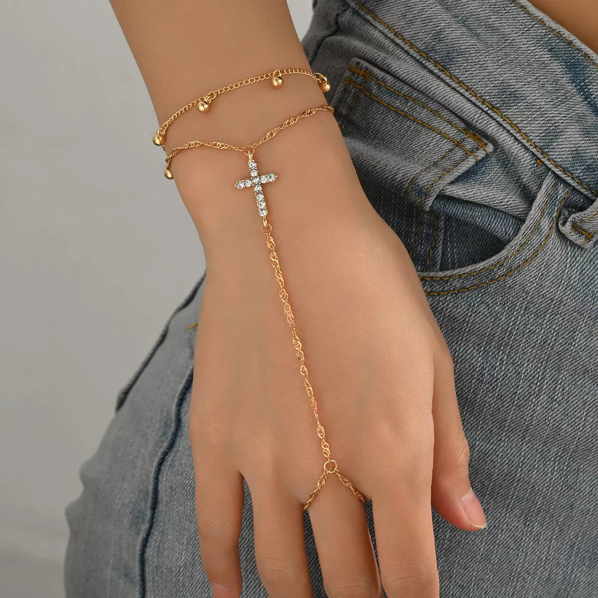 Cross bracelet shown dangling along the wrist with layered chains