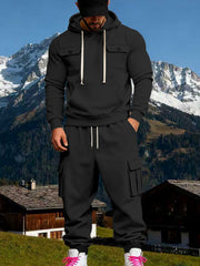 Front view of a model in a black hoodie and matching black cargo sweatpants outdoors