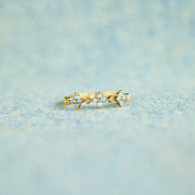 Gold-tone sterling silver flower ring with blue and clear stones on pale fabric
