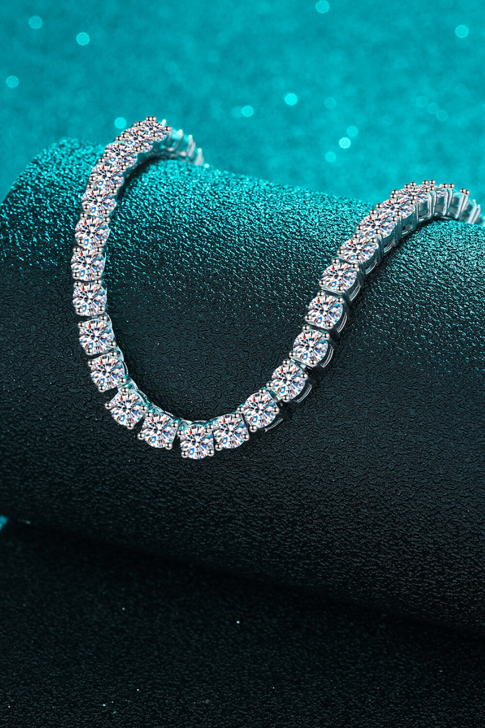 Rhodium-tone moissanite necklace draped over dark display surface
