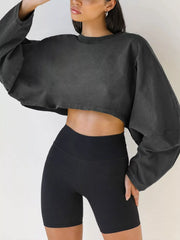 Long sleeve charcoal cropped sweatshirt worn with black shorts, front view