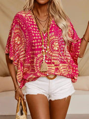 Front view of a pink medallion-print V-neck blouse with tassel ties, worn with white shorts.