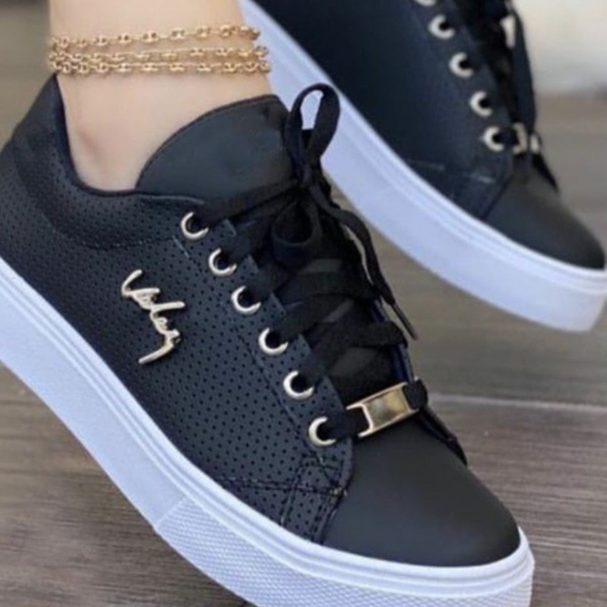 Close view of black perforated lace-up sneaker with metal eyelets and decorative side accent