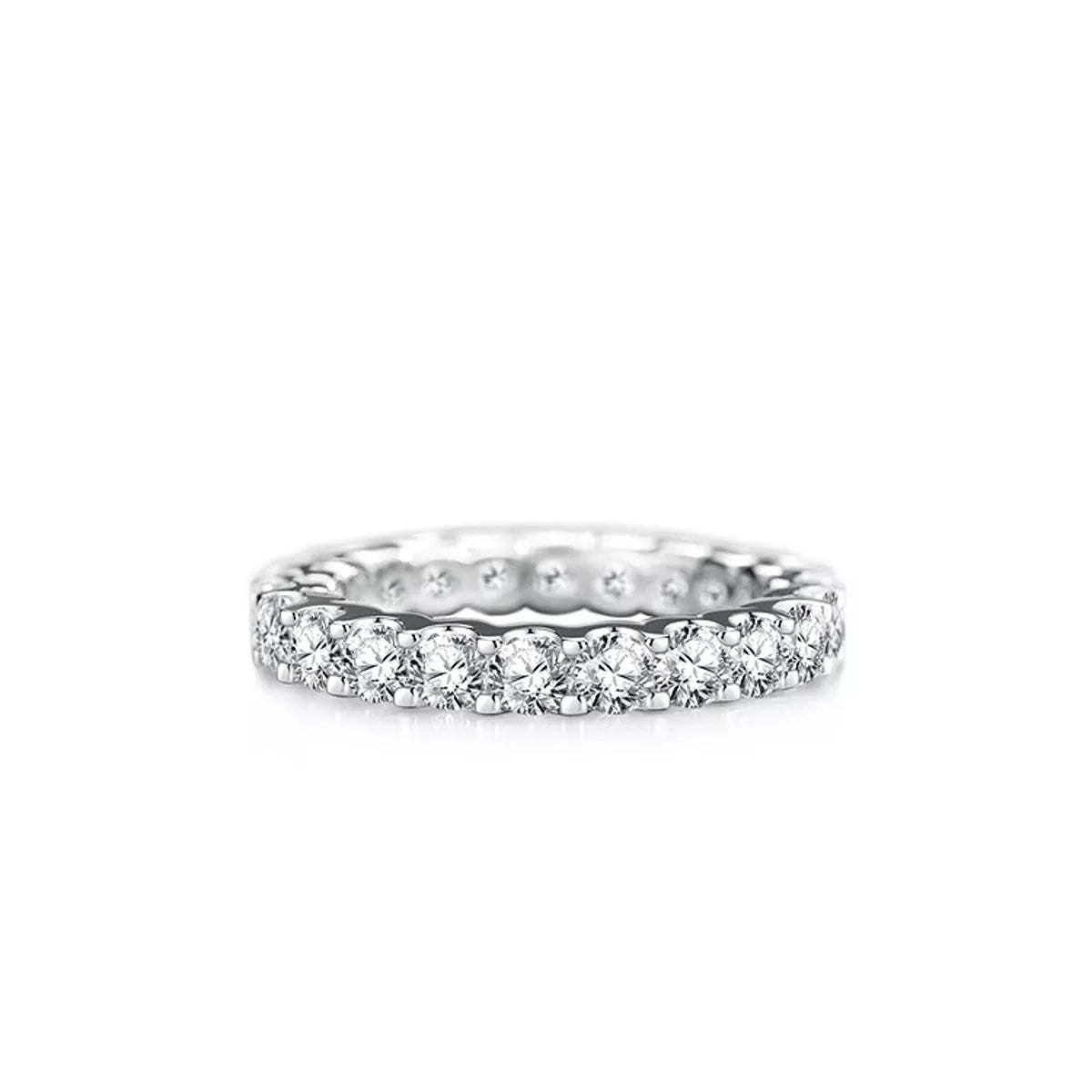 Close-up of the pink center stone and pavé-set shoulders on a silver ring displayed over a turquoise ribbon.