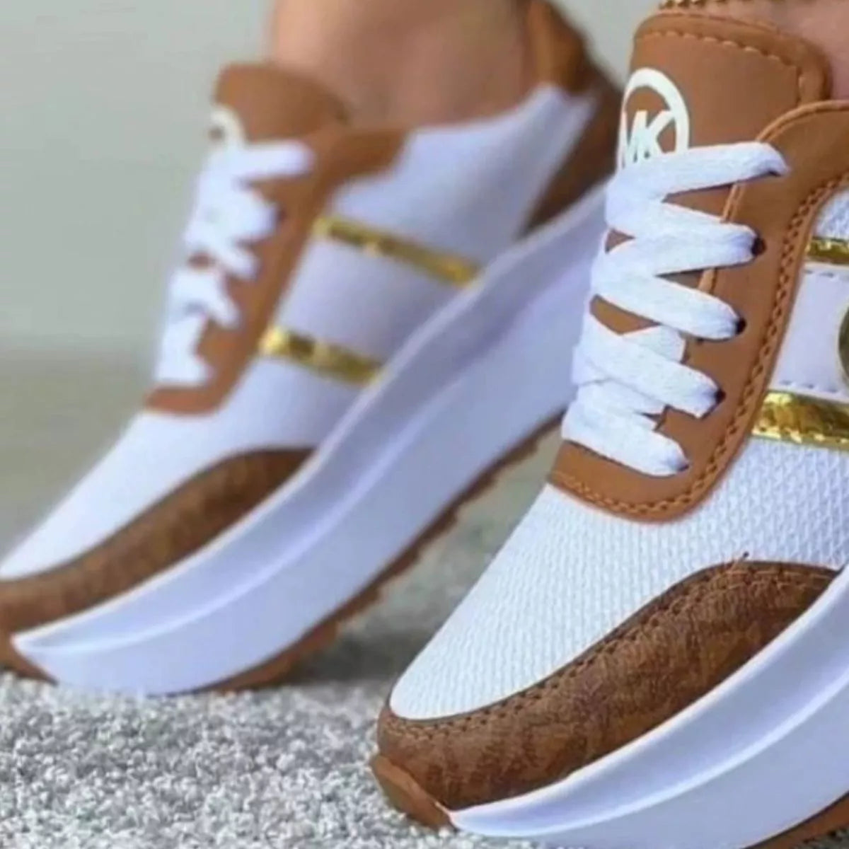Close-up of brown panels and gold trim on white sneakers