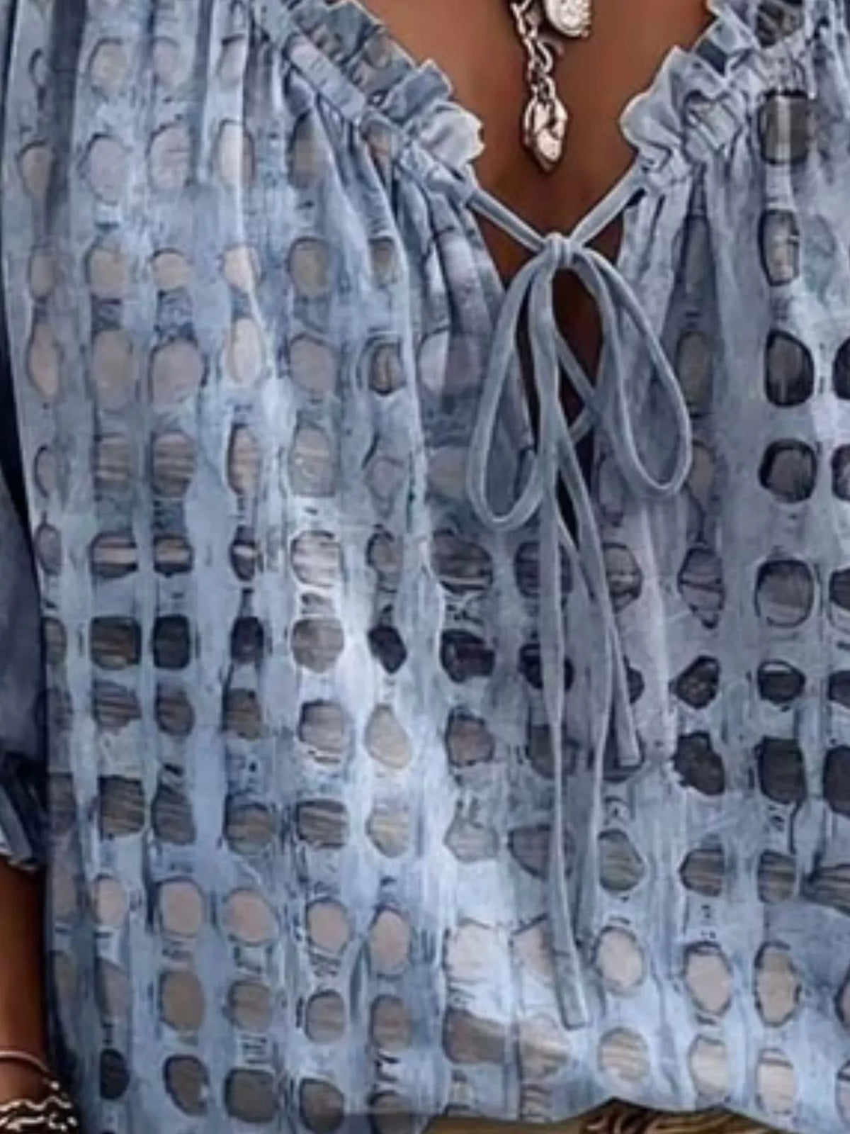 Close view of blue spotted blouse showing ruffle-trimmed tie neckline and sleeve