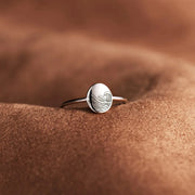 Close-up of engraved round face ring on textured brown surface