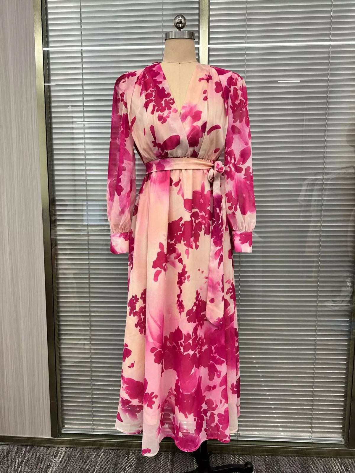 Pink floral long-sleeve maxi dress displayed from the front on a dress form.