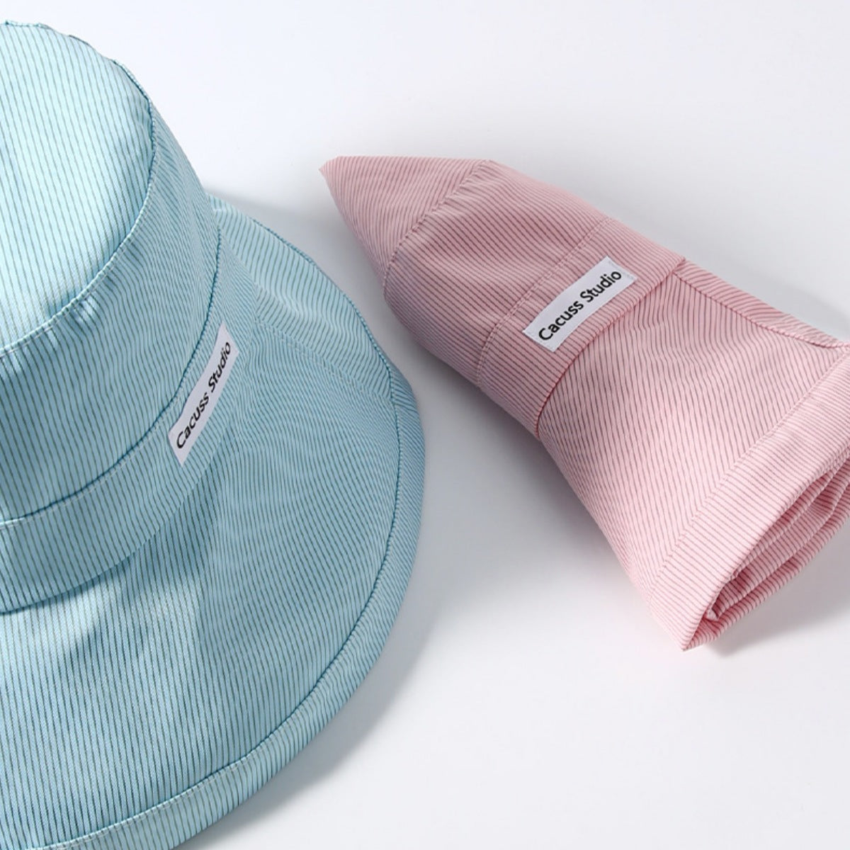 Mint green and pink wide-brim hats shown close-up, with the pink hat folded.