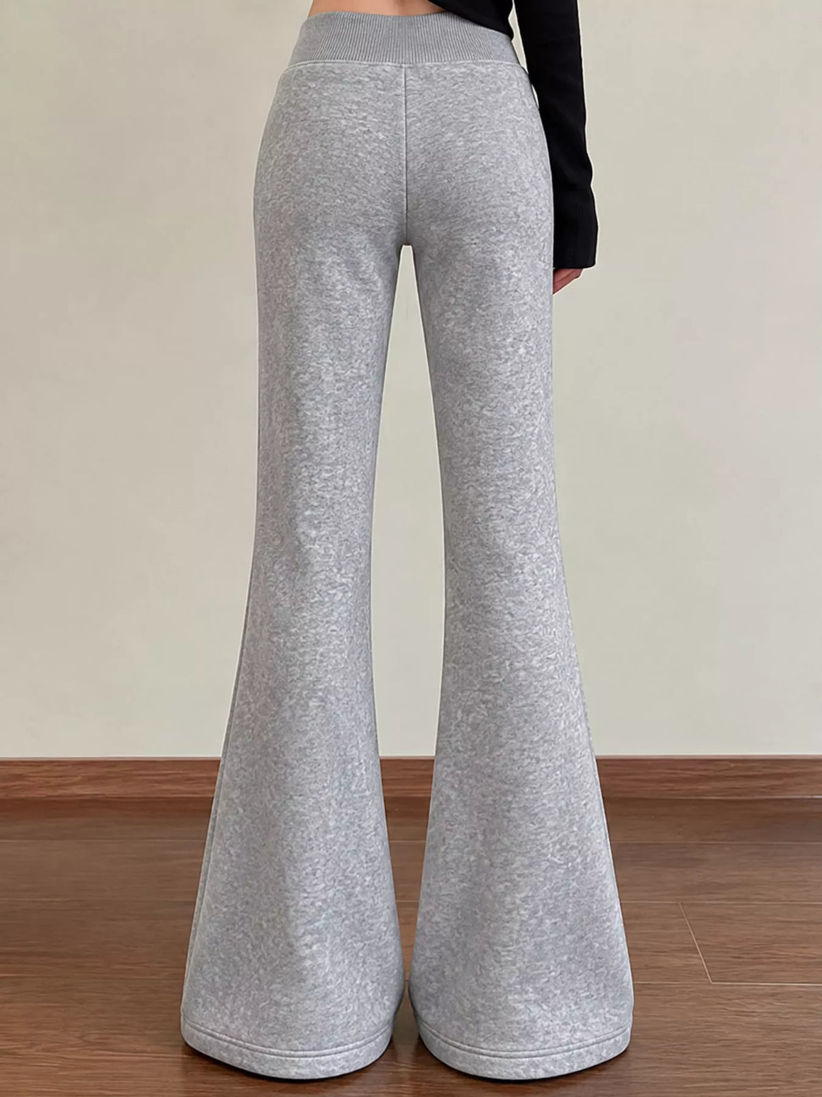 Rear view of grey flared trousers showing wide legs and an elastic waistband