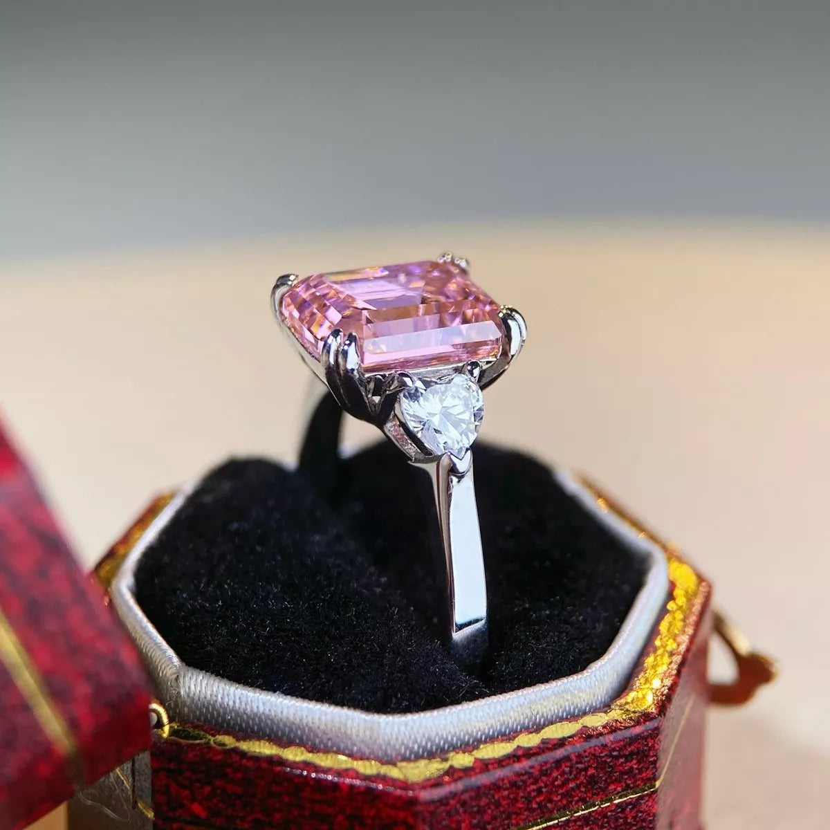 Pink emerald-cut ring shown in profile with raised center setting