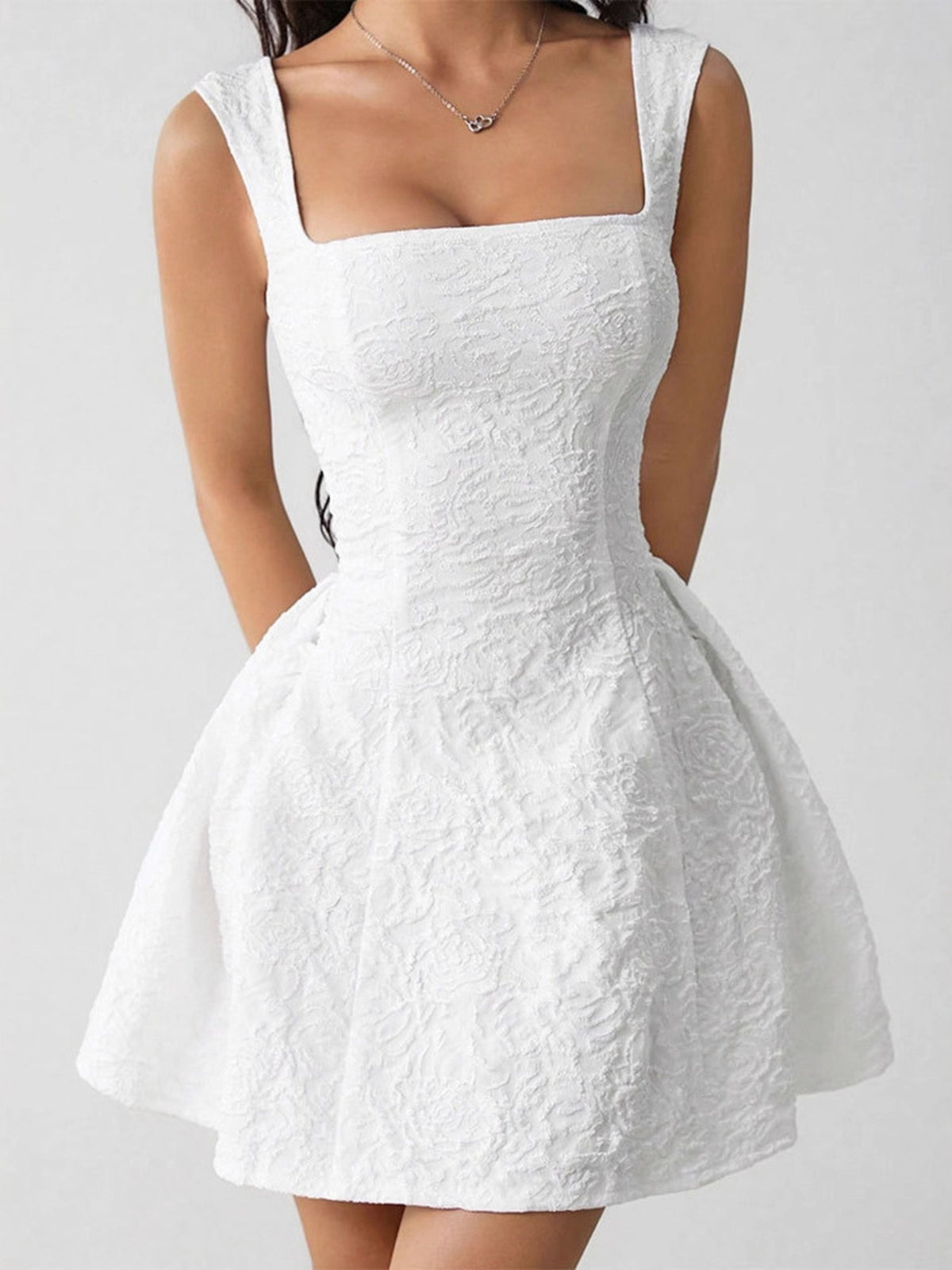 Front view of white textured square-neck mini dress with wide straps and flared skirt