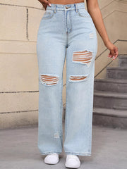Straight-on view of pale blue distressed jeans with ripped knees and white trainers