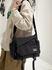 Black fine-check messenger bag worn over the shoulder on a wide adjustable strap