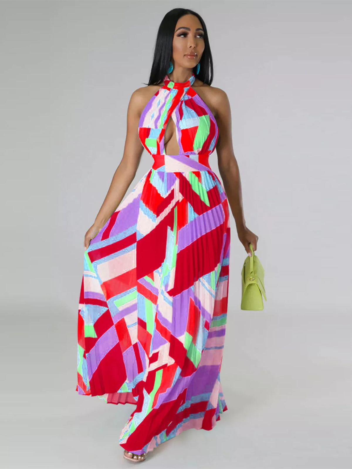 Front view of a red and pink pleated halter maxi dress, with a model holding the skirt outward.