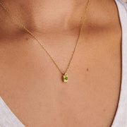 Small yellow-green rectangular pendant on a gold-tone chain worn at the neckline