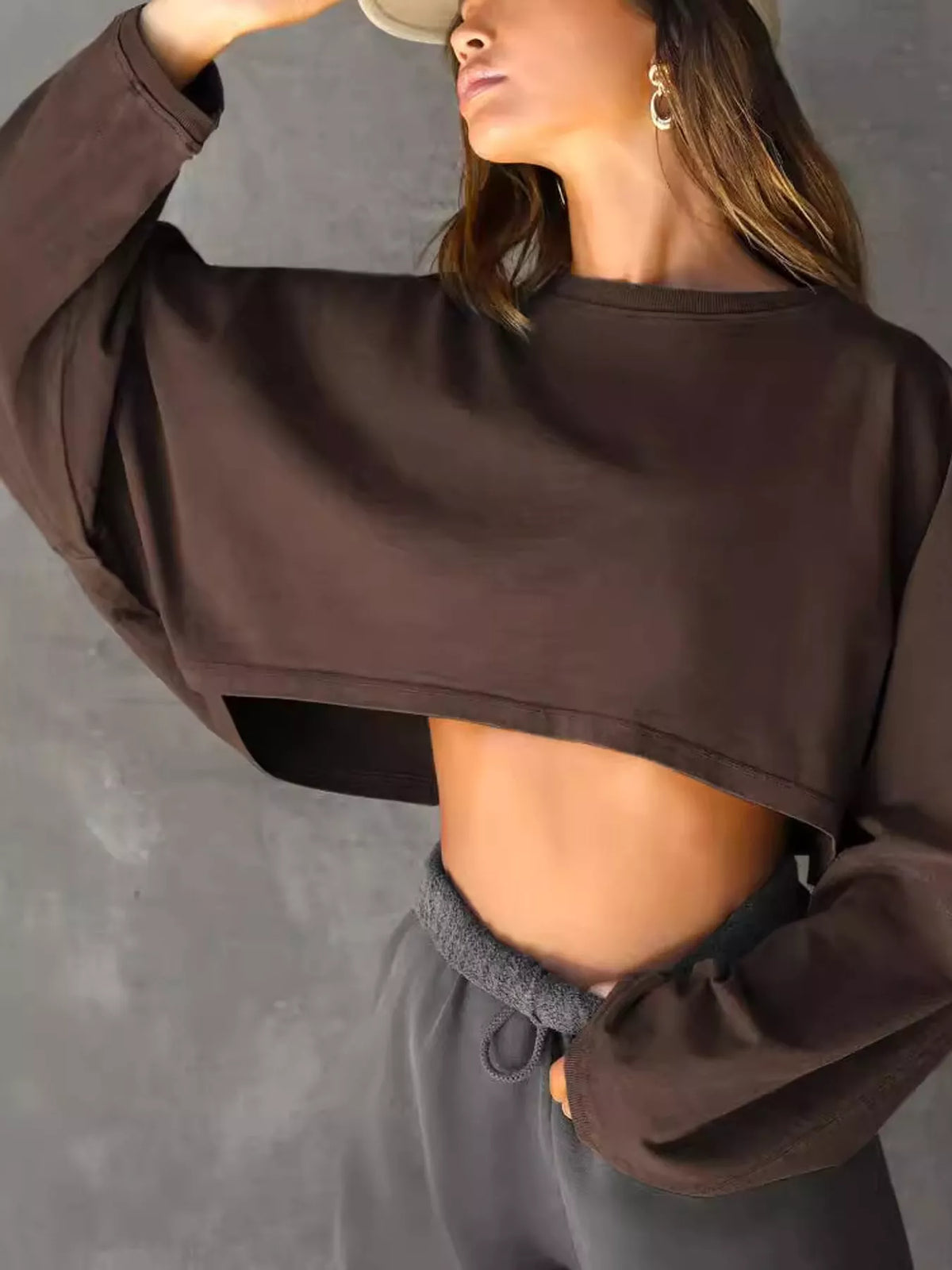 Angled view of dark brown cropped sweatshirt with oversized sleeves