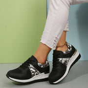 Black floral-panel sneakers worn in a side view