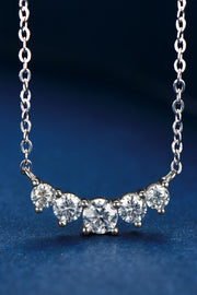 Close view of curved moissanite necklace on blue background