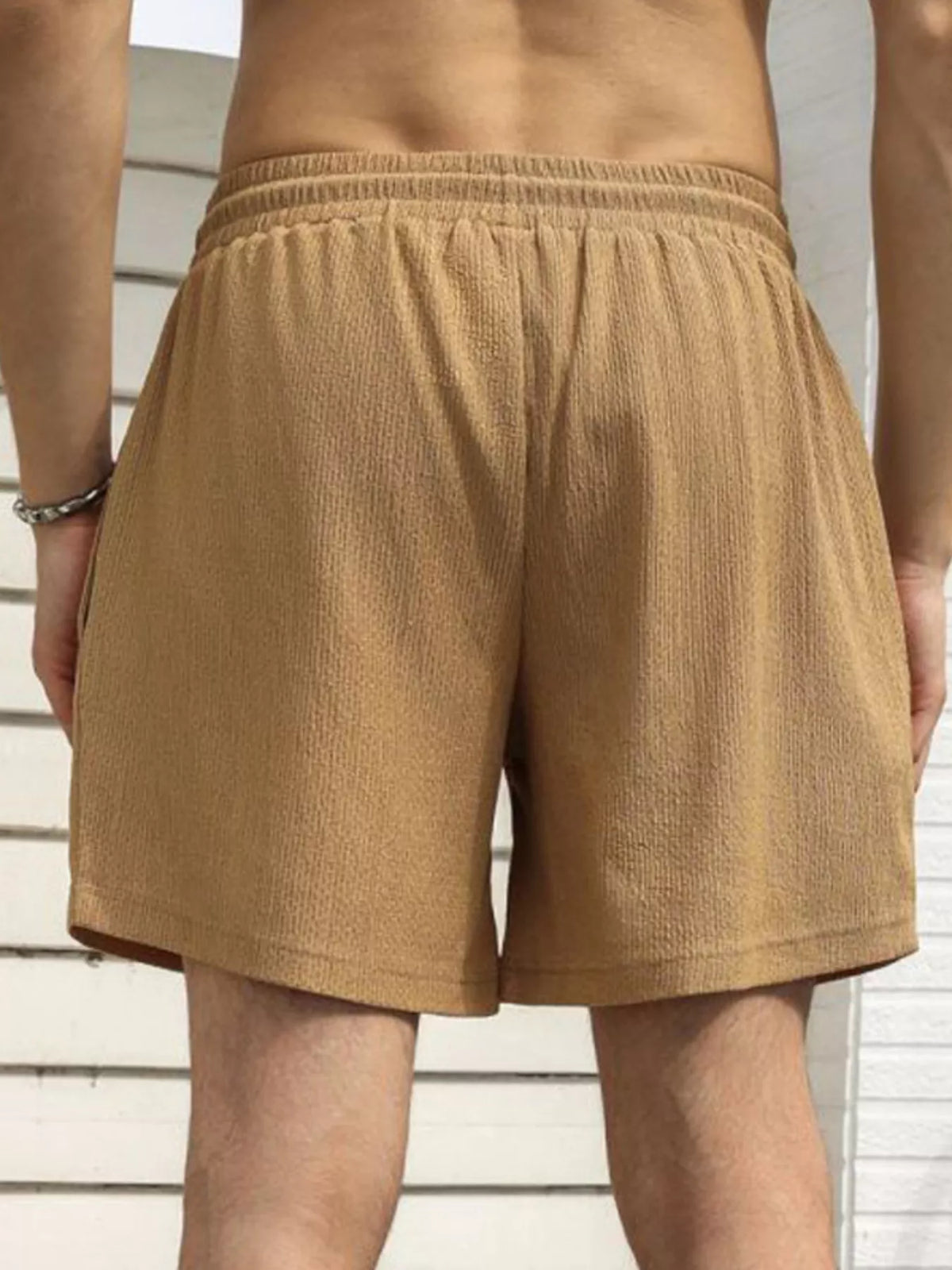 Model wearing tan drawstring shorts, back view