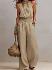 Model wearing a beige halter-neck jumpsuit with smocked waist and wide legs