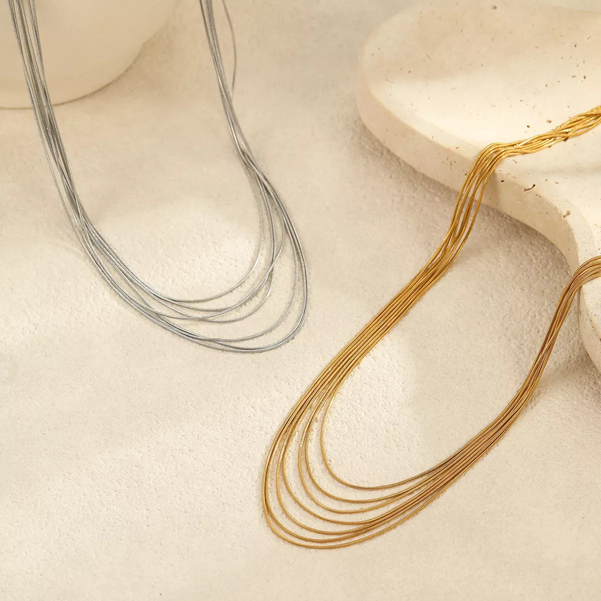 Gold-tone and silver-tone multi-strand necklaces laid out side by side