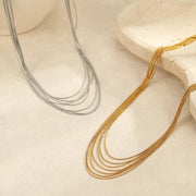 Gold-tone and silver-tone multi-strand necklaces laid out side by side
