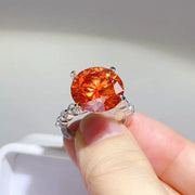 Close-up of orange-red round centre stone ring held in hand