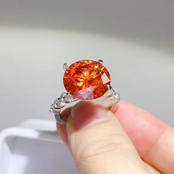 Close-up of orange-red round centre stone ring held in hand