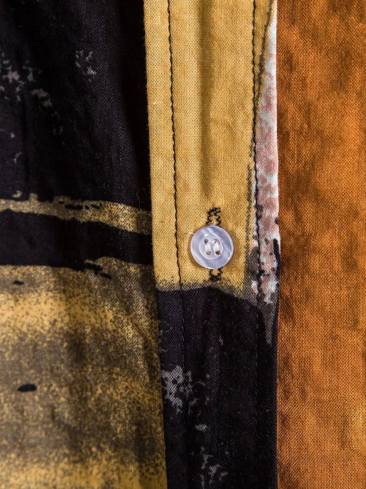 Close-up of a button on the black and ochre shirt placket