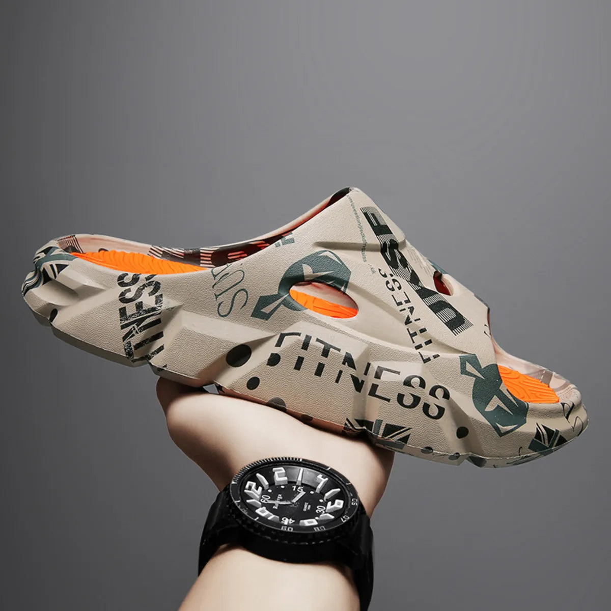 Beige printed platform slide held at an angle showing side ventilation and orange footbed