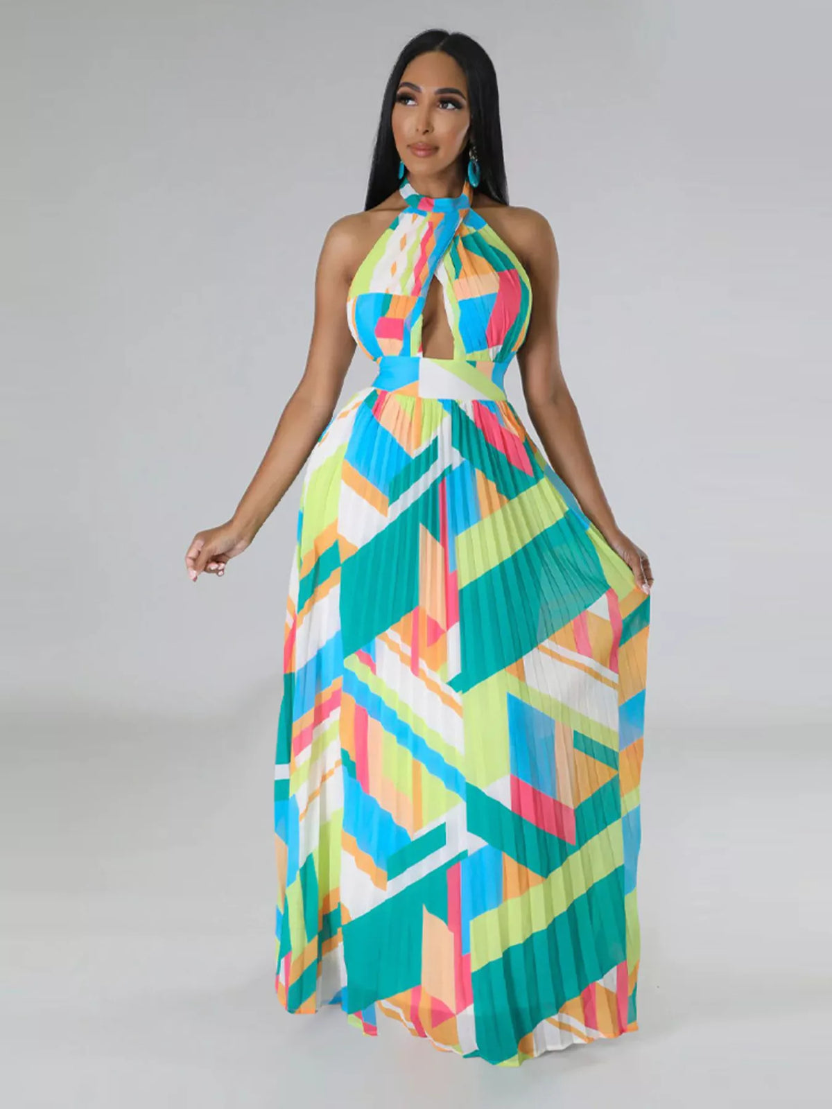 Turquoise and yellow geometric halter maxi dress on a model, with the skirt held to one side.