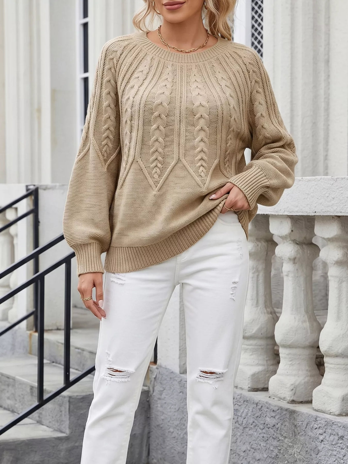 Beige cable-knit sweater worn with white jeans, front view