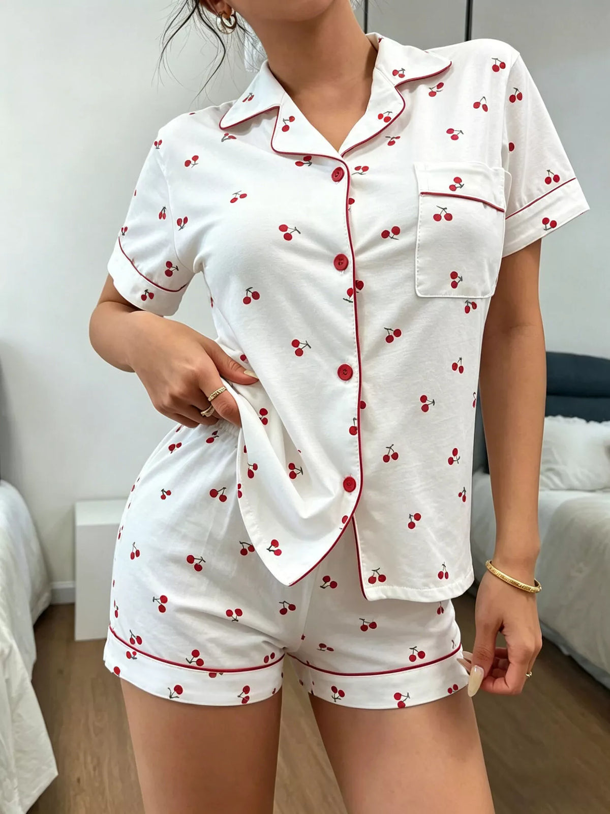 White cherry-print button-down pajama shirt and matching shorts on model