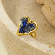 Gold-plated heart ring with blue and pink stones on a light surface