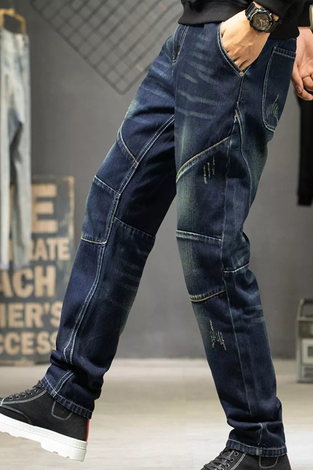 Angled view of dark blue straight-leg jeans showing faded thighs and stitched knee panels